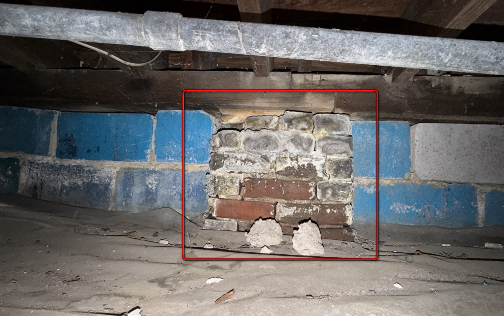 Aging masonry foundation pier with spalling brick and crumbling mortar.