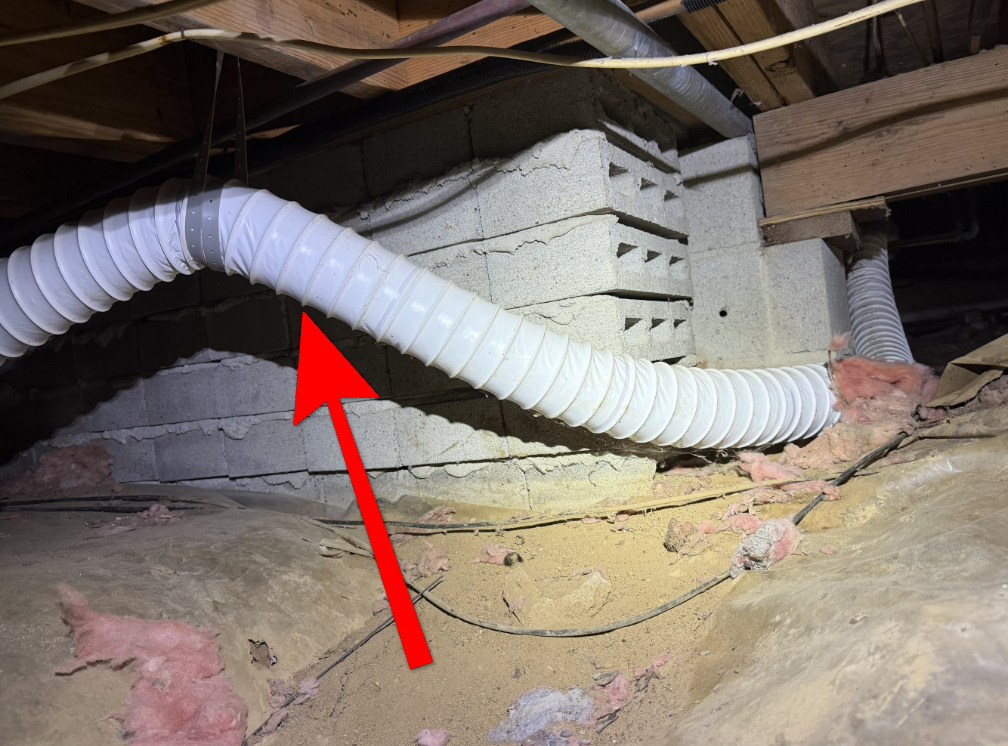 Combustible vinyl flexible dryer vent hose routed in crawl space.