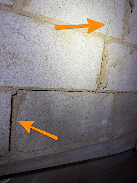 Step crack running along exterior brick foundation mortar joints.