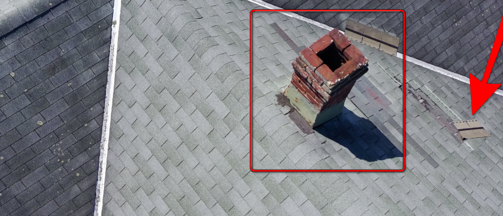 Damaged asphalt roof shingles next to crumbling chimney mortar.